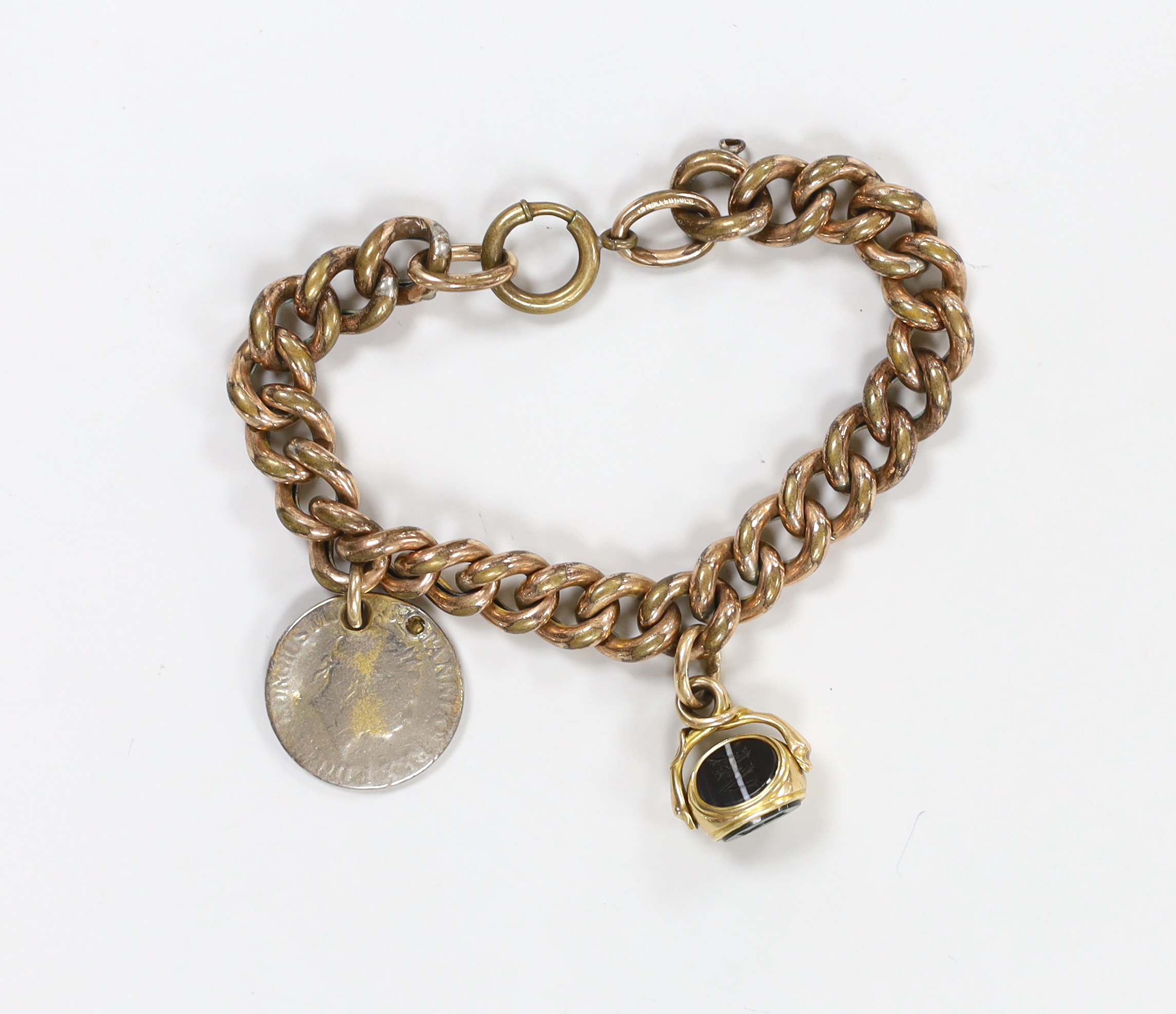 A Victorian gilt metal curb link bracelet, hung with a yellow metal and chalcedony set spinning fob and a worn coin.